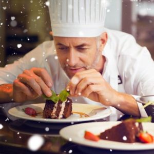 Snow against concentrated male pastry chef decorating dessert in kitchen