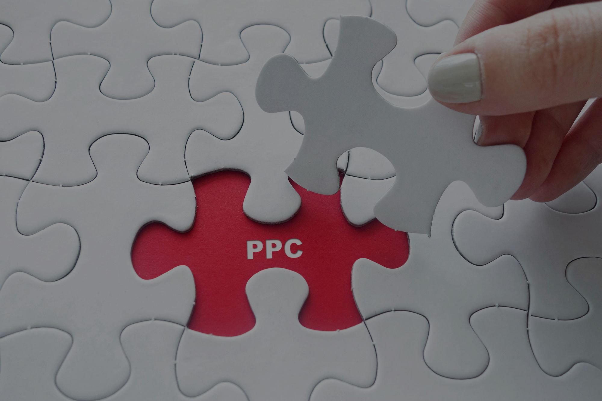 Close up of girl’s hand placing the last jigsaw puzzle piece with word PPC